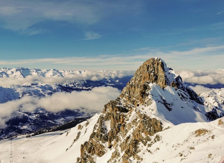 Snow-covered Alpine peaks rising above the clouds near Courchevel in the French Alps