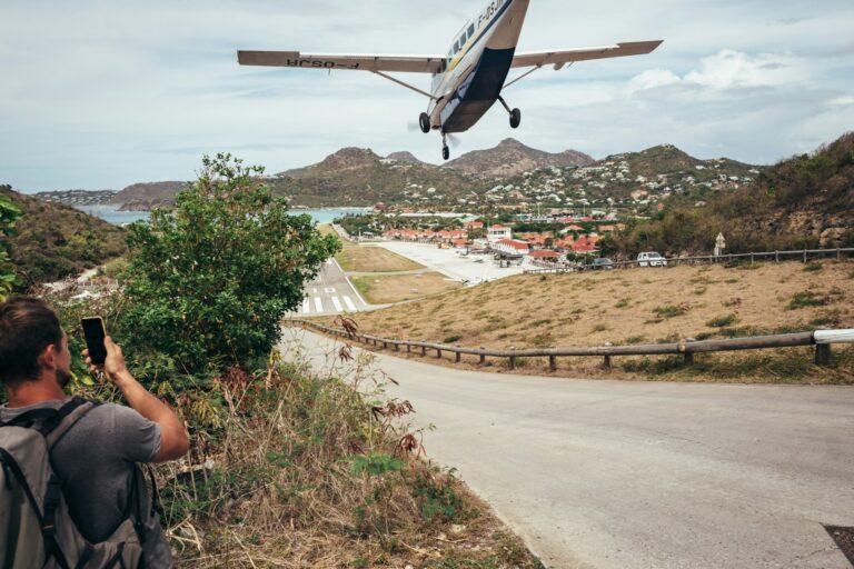 A spectator photographs a small aircraft landing on a short island runway